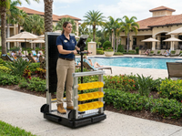 Worker riding the TexTrack powered material handling cart through a narrow facility aisle